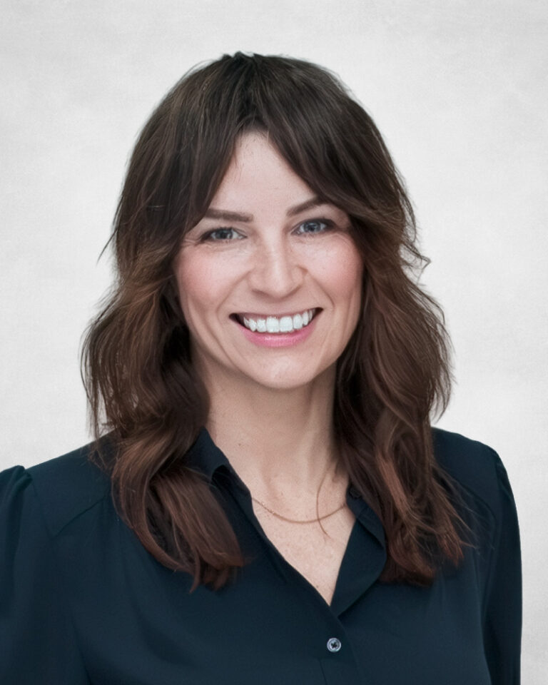 Danielle Rae is a woman with wavy brown hair. She is wearing a dark blouse and a thin necklace.