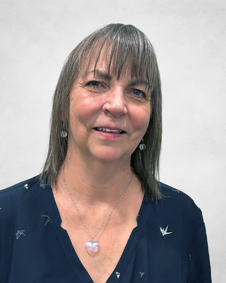 Franchise Miller is a middle-aged woman with straight, shoulder-length light brown hair. She wears a navy blouse with a heart-shaped pendant necklace and small earrings.