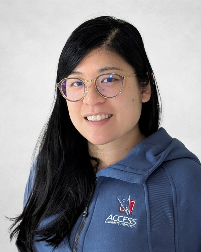 Jay Pang has long black hair and round glasses. They are wearing a blue sweater with the Access Community Therapists logo on it.