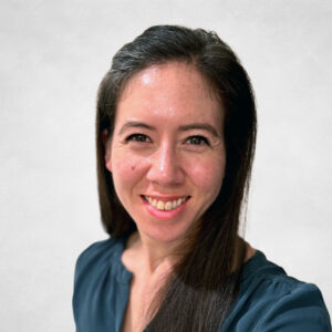 Natasha Chow, A woman with long dark hair and a dark blue blouse smiles at the camera against a plain light background.