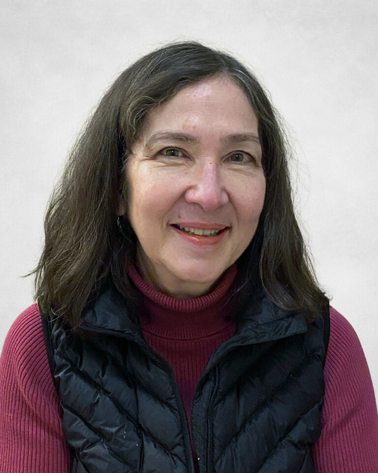 Regina Colistro is a woman with medium-length brown hair. She is wearing a maroon polo-neck jumper and a black quilted gilet.