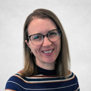 Renee van Doorninck, A woman with straight, shoulder-length brown hair and glasses smiles at the camera. She is wearing a ribbed jumper with horizontal stripes in blue, orange, white, and brown against a light background.